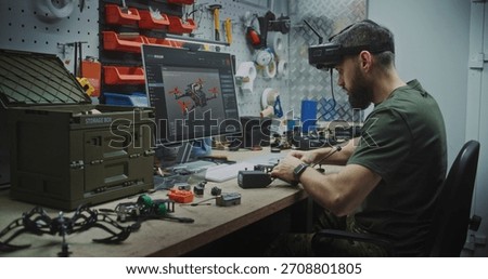 Engineer Using VR Goggles to Virtually Design. Man in Military Style Uniform Utilizing VR Goggles and Computer While Assembling Drone Components. Concept Integration of Virtual Tools in Engineering.