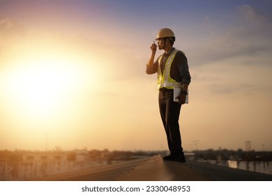 Engineer using walkie talkie and talking about work construction site. talking by walkie talkie control and communicate with worker. Contractor man using radio operation in industry. - Powered by Shutterstock