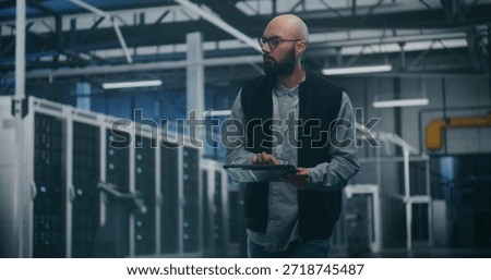 Engineer Utilizing Software in Data Center. Professional Male Engineer Uses Specialized App on Tablet to Monitor Performance of Enterprise Level Servers. Modern IT Tools and Technical Supervision.