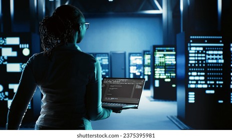 Engineer walking in server room housing advanced infrastructure storing massive datasets. Worker running code on tablet to upgrade data center rigs doing complex computational operations - Powered by Shutterstock