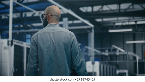 Engineer Walking Through Tech Enterprise Center. Bearded Professional Walking Steadily Through Brightly Lit Hall of Large Tech Enterprise Center. High Tech Work Environment and Maintenance Rounds.