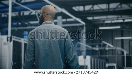 Engineer Walking Through Tech Enterprise Center. Bearded Professional Walking Steadily Through Brightly Lit Hall of Large Tech Enterprise Center. High Tech Work Environment and Maintenance Rounds.
