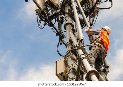 engineer wear safety equipment working with smart phone on high telecommunication tower.