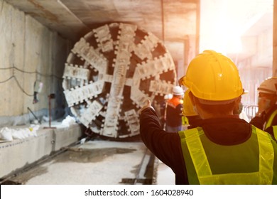 Engineer Wear Yellow Helmets,vests  Safety Are Discussing.Technician Control Underground Tunnel Construction At Working Shaft.Transport Pipeline By Tunnel Boring Machine(TBM) Method For Electric Train