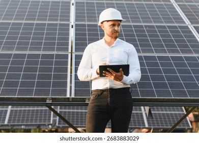 Engineer wearing a hard hat, checking photovoltaic panels with a digital tablet. Representing renewable energy and sustainable technology - Powered by Shutterstock - Get 15% off with code: PIKWIZARD15