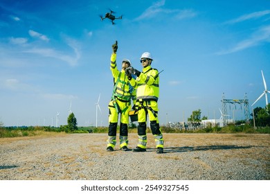 An engineer wearing safety gear closely inspects the base of a wind turbine in a renewable energy field. - Powered by Shutterstock