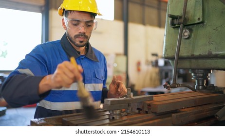 Engineer Wearing Safety Helmet And Glasses Standing In The Production Of Manufacturing Factory. Remove Metal Chip From The Machine. Industrial And Cleaning Concept. Happy Job And Good Workplace