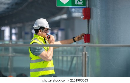 Engineer wearing safety uniform and helmet under checking fire evacuation alarm emergency system in industry factory and exit door is factory security protection concept. - Shutterstock ID 2151993563