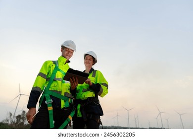 Engineer wearing safety uniform using tablet discussed plan about renewable energy at station energy power wind turbine. technology protect environment reduce global warming problems.
