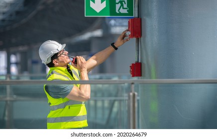 Engineer wearing safety unifrom and helmet under checking fire alarm emergency system in industry factory and exit door is factory security protection concept.