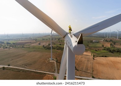 Engineer wearing uniform hold equipment box standing a top of windmill and looking inspection work in wind turbine farms rotation to generate electricity energy. - Powered by Shutterstock