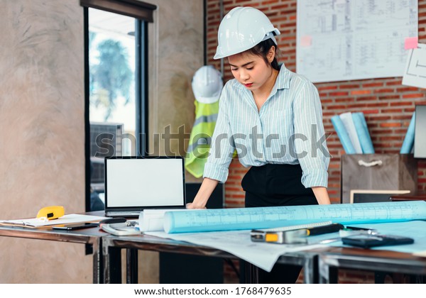 Engineer\
woman read drawing blue print on table workplace at room site\
construction. Engineer architect plan\
concept.