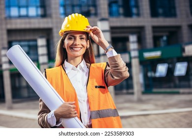 Engineer woman in safety equipment  holding plans. Building, developing, construction and architecture concept. - Powered by Shutterstock