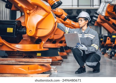 Engineer woman working in advance machine factory. Indian female engineering staff work checking robot arm in assembly plant