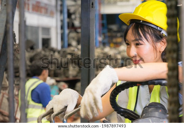 Engineer woman working, Asian engineer\
worker woman wear helmet for safety,  drive forklift and look left\
side in\
factory-warehouse