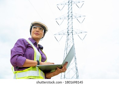 Engineer women using Laptop checking voltage pole Power Transmission. - Powered by Shutterstock