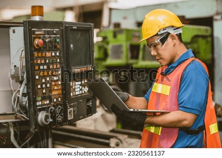 Engineer worker check service panel program operate CNC lathe machine with laptop computer fix repair old machine.