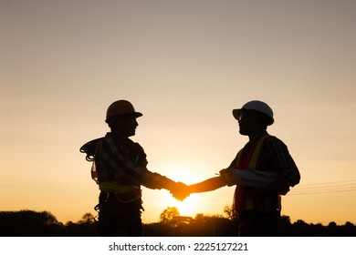 Engineer and worker handshake at construction site silhouette