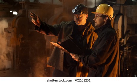 Engineer And Worker Have Conversation In Foundry. Rough Industrial Environment. Middle Shot.