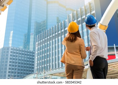 Engineer and worker with helmet looking at construction site.