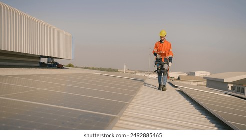 engineer worker in a high-visibility vest walks along a solar panel array on a building roof - Powered by Shutterstock