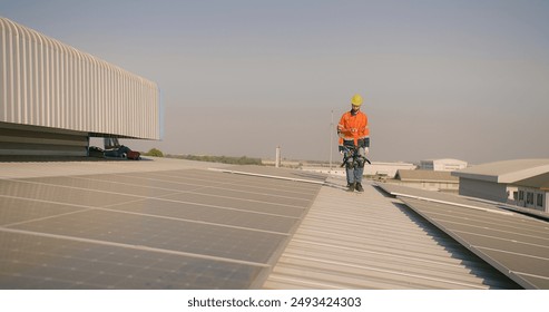 engineer worker in a high-visibility vest walks along a solar panel array on a building roof - Powered by Shutterstock