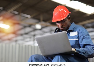 Engineer Or Worker Man In Protective Uniform Sitting And Using Computer While Pose Thinking Something And Controlling Work With Hardhat And Electric Cable Line At Heavy Industry Manufacturing Factory