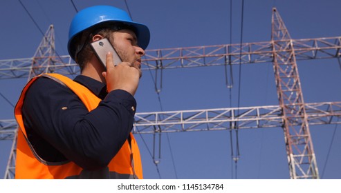 Engineer Worker Man Talking On Mobile Phone With Electricity Pylon Power Wire Lines Network