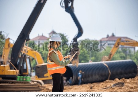 Engineer worker operations construction plans large black drainage pipe installing underground infrastructure heavy machinery importance of careful planning and teamwork in construction project.