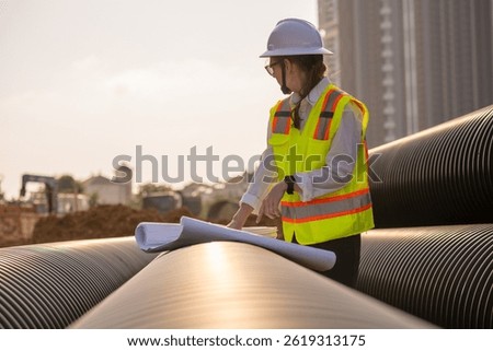 Engineer worker operations construction plans large black drainage pipe installing underground infrastructure heavy machinery importance of careful planning and teamwork in construction project.