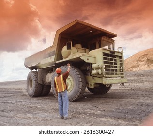 Engineer worker stand behind mining big monster truck.