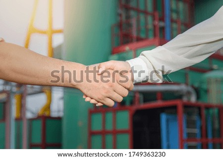 Engineer and worker team making handshake together to agree joint business at power plant site.
