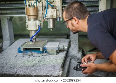 Engineer worker technician operating with CNC milling metal engraving machine in factory workshop.