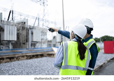 An engineer is working at high voltage power substation performing inspection and check of infrastructure to ensure safety and proper operation of electrical system