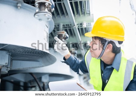 An engineer is working at high voltage power substation performing inspection and check of infrastructure to ensure safety and proper operation of electrical system