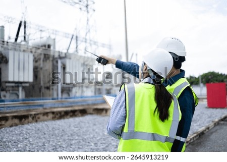 An engineer is working at high voltage power substation performing inspection and check of infrastructure to ensure safety and proper operation of electrical system