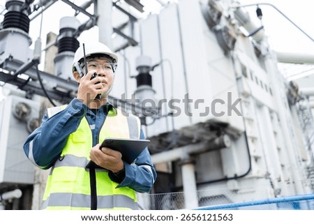 An engineer is working at high voltage power substation performing inspection and check of infrastructure to ensure safety and proper operation of electrical system