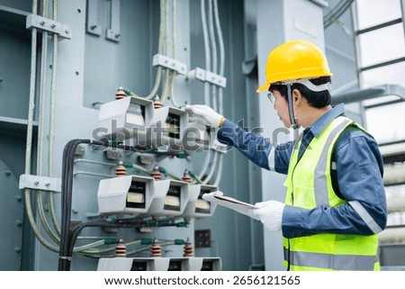 An engineer is working at high voltage power substation performing inspection and check on electrical infrastructure to ensure safety and proper operation