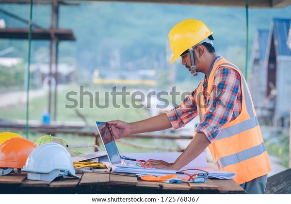 Engineer working with laptop and\
blueprints,engineer inspection in construction site for\
architectural plan,sketching a construction project.\
