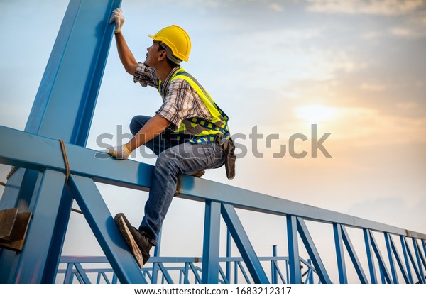Engineer working in a metal roof\
structure,Construction engineer wear safety uniform inspection\
metal roofing work for\
industrial.