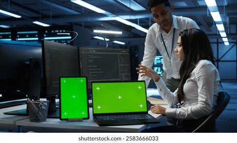 Engineer working with mockup laptop and tablet in data center used for managing gear energy consumption. Employee using green screen devices in workplace used for automation in server farm, camera B