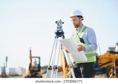 Engineer working on a construction project, checking building plans with a surveying instrument and heavy machinery in background