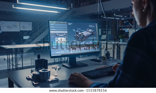 Engineer Working on\
Desktop Computer, Screen Showing CAD Software with Car Efficiency\
and Engine Concept. Industrial Design Engineering Facility. Over\
the Shoulder Shot