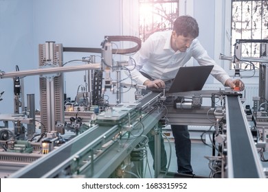 Engineer Is Working On Laptop To Program Smart Factory Prototype's Automation. Automated Car On Production Line, Artificial Intelligence In Smart Manufacturing. Industry 4.0 Concept.