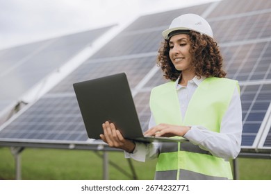 Engineer working on a laptop while inspecting a solar power station, contributing to renewable energy and sustainable development efforts