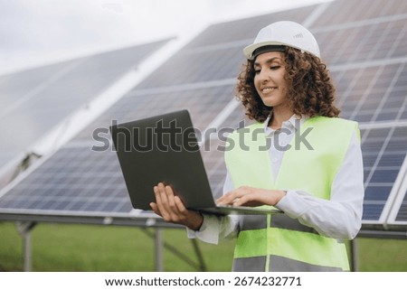 Engineer working on a laptop while inspecting a solar power station, contributing to renewable energy and sustainable development efforts