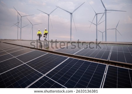Engineer working on solar cell plant with windmill field.Solar cell smart grid and windmill are ecology energy renewable sunlight alternative green power environment factory concept