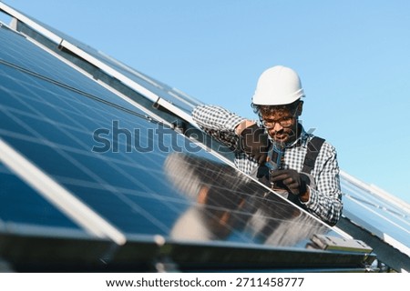 Engineer working on a solar panel installation, using a screwdriver to tighten screws on a photovoltaic power plant