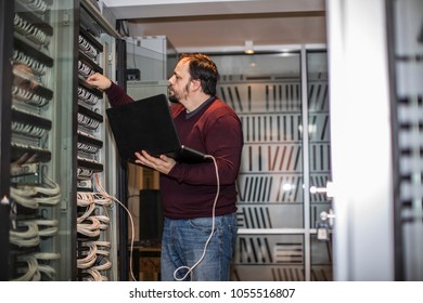 Engineer working in server room - Shutterstock ID 1055516807