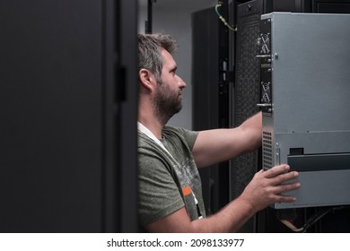 IT engineer working In the server room or data center The technician puts in a rack a new server of corporate business mainframe supercomputer or cryptocurrency mining farm. 